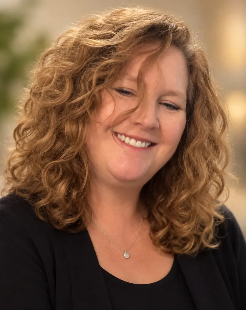 Author Barbara Grace, smiling, with curly auburn hair
